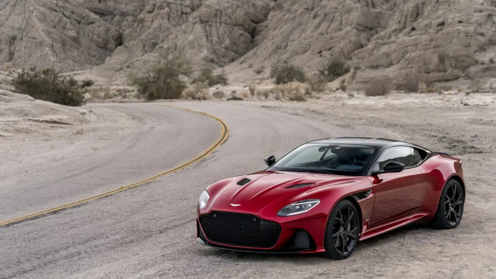 A new, red Aston Martin DBS Superleggera parked in the desert.