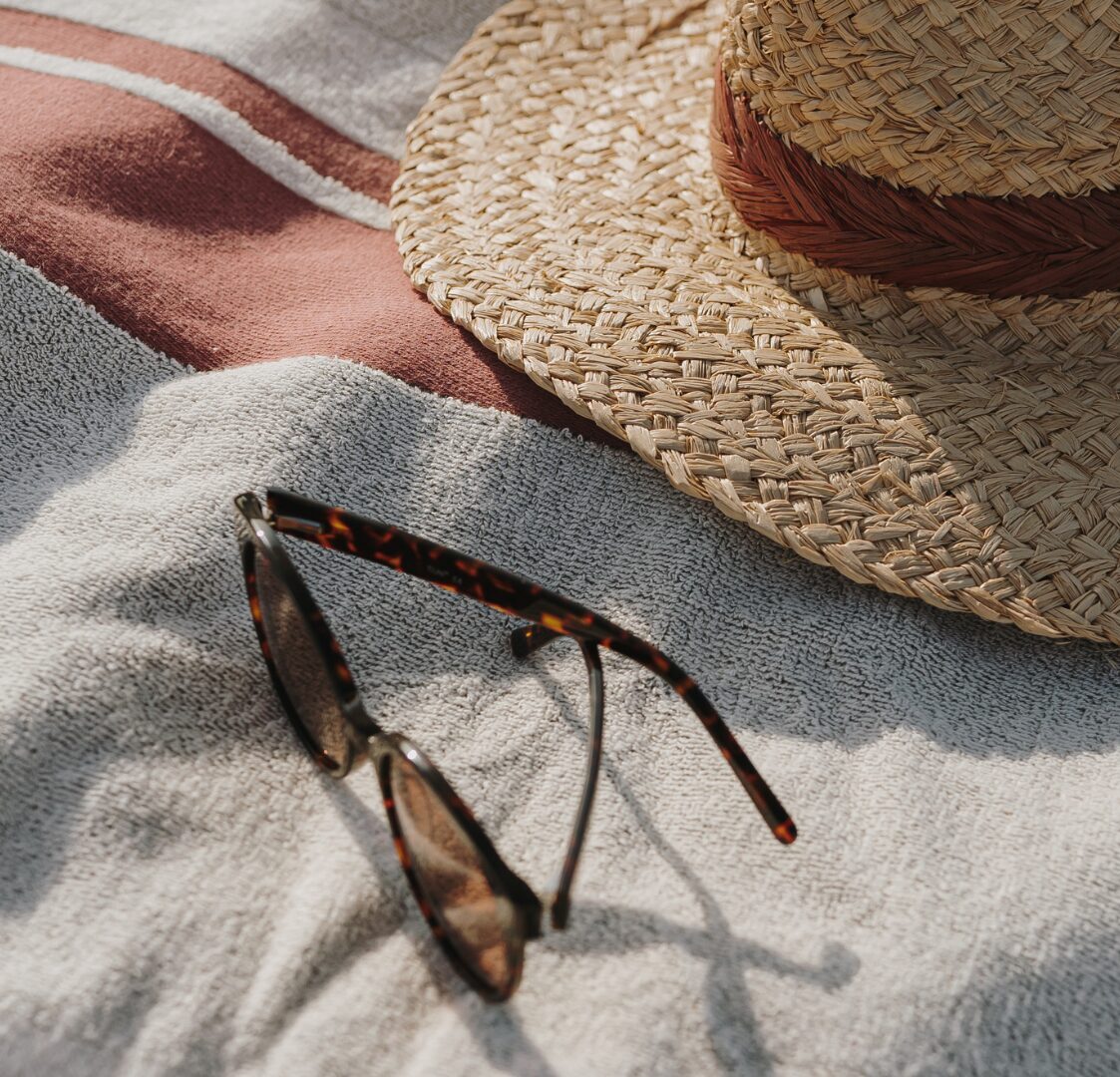A pair of sunglasses and a summer hat on a sunlounger.