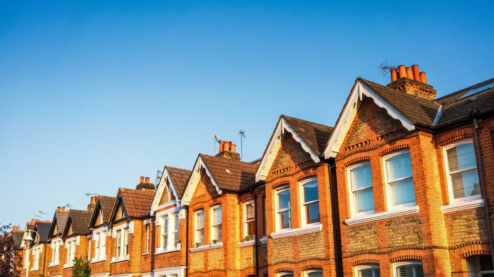 A row of terraced homes in the UK with blue skies in the background.