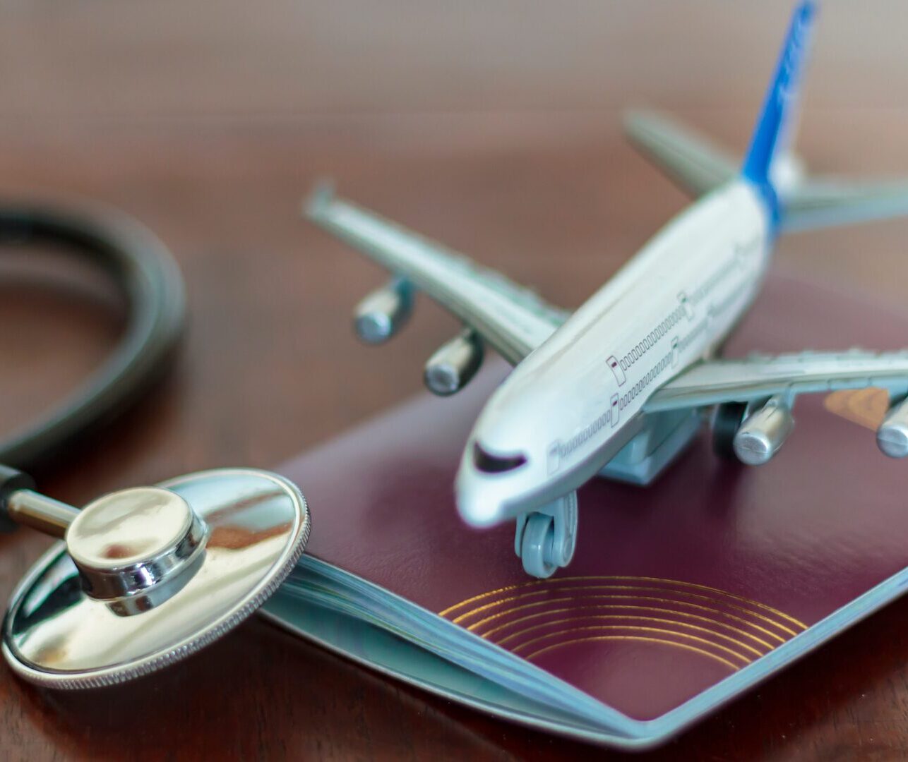 A photo of a plane on top of a passport and next to a stethoscope.